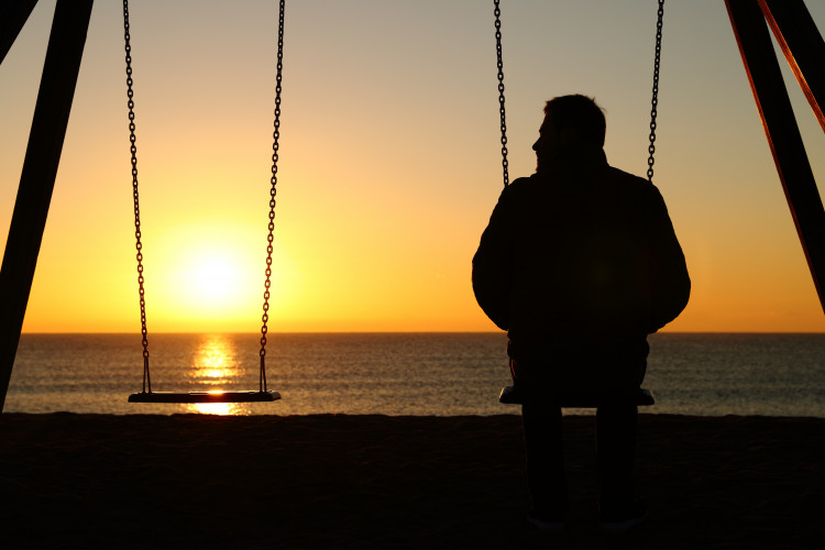 Mann auf einer Schaukel vor dem Meer